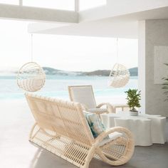 a wicker chair sitting on top of a white floor next to a table with a potted plant