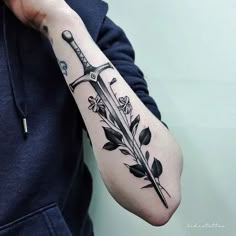 a person with a tattoo on their arm holding a knife and flower arrangement in front of them