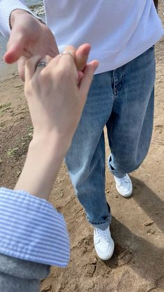 two people standing next to each other on the beach holding hands and touching their fingers