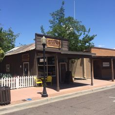 a small building with a white picket fence around it's sides and trees in the background