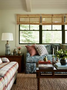 a living room filled with furniture and pillows on top of a rug next to a window