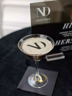 a martini glass sitting on top of a table next to a black and white sign