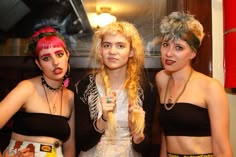 three young women dressed in costume posing for the camera with their hair pulled up and makeup painted