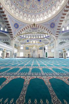 the interior of a mosque with an ornate ceiling and carpeted floor, with arabic writing on