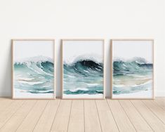 three framed art prints on the wall above a wooden floor in front of a white wall