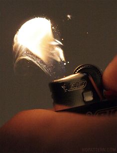 a person holding a lighter in their hand with the light shining on it's side