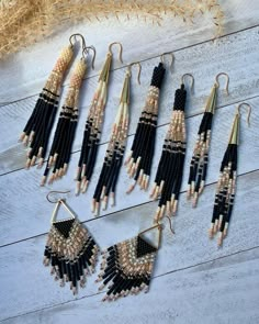 six pairs of beaded earrings hanging from hooks on a wooden surface with corn stalks in the background