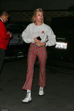 a woman in plaid pants is standing outside