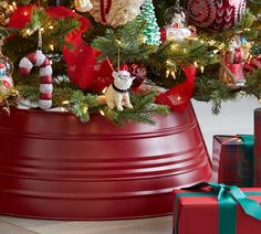 a christmas tree in a red bucket with presents around it and an ornament on the top