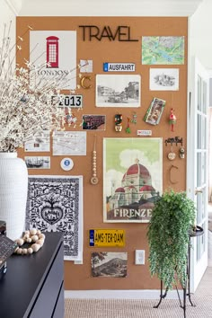 a cork board with pictures and magnets on it in a living room next to a potted plant