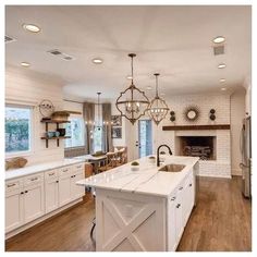 a large kitchen with white cabinets and an island in the middle, along with a fireplace