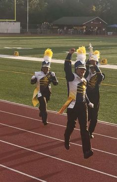 some young people are running on a track with their hands in the air while wearing cheerleader costumes