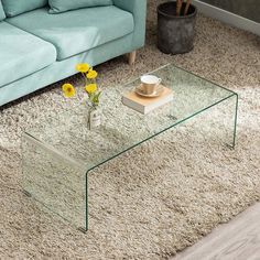 a glass coffee table sitting on top of a carpeted floor next to a blue couch