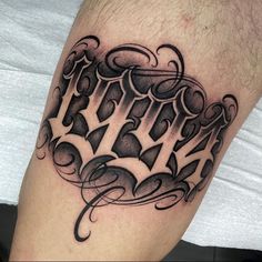 a black and white tattoo on the leg of a man with an ornate font design