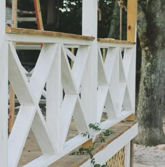 a wooden deck with white railings and trees in the backgroung area