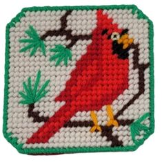 a red bird sitting on top of a green and white square with leaves around it