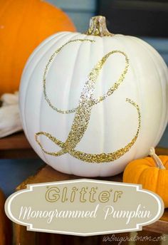 a white pumpkin decorated with gold glitter monogrammed pumpkins on a wooden table