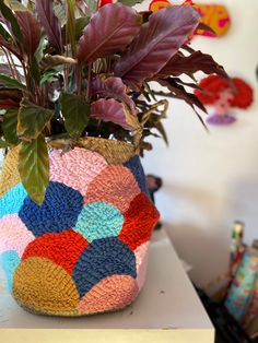 a potted plant sitting on top of a white table next to a colorful vase