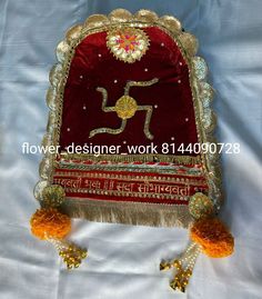 a red and gold chair with tassels on the legs, sitting on a white sheet