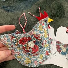 a hand holding an ornament made out of fabric and paper with a bird on it