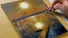 a person is painting a sunset scene on a piece of paper with paintbrushes