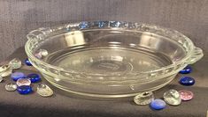 a glass bowl filled with lots of blue and purple beads on top of a table