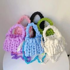 four different colored braided bags sitting on top of a white table next to each other