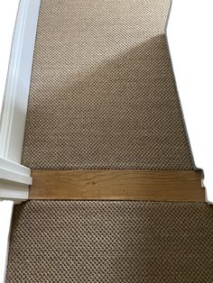 a close up view of a carpeted stair tread with a wooden strip on the bottom