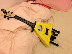 a yellow triangle shaped instrument laying on top of a white bed with pink sheets and pillows