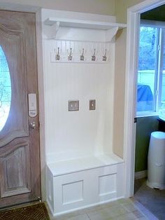 an entryway with a bench and wine glasses on the door