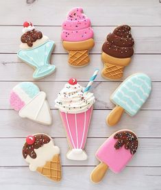 decorated cookies arranged in the shape of ice cream and desserts on a white wooden table