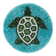 a sea turtle made out of glass beads on a blue and white plate with green accents