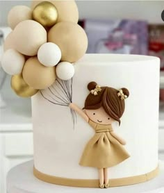 a white cake topped with a girl holding balloons