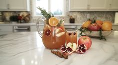 two pitchers filled with liquid sitting on top of a counter next to sliced apples and cinnamons