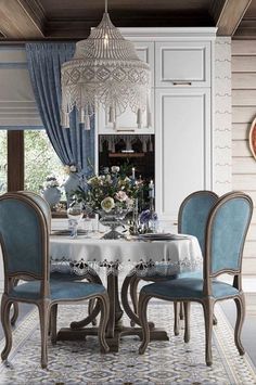 a dining room table with blue chairs and a chandelier hanging from the ceiling