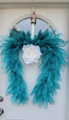 a blue wreath with white flowers hanging on a door