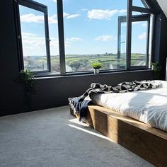 a bed sitting under two large windows next to a window sill in a bedroom