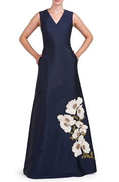 a woman in a long blue dress with white flowers on the front and back side