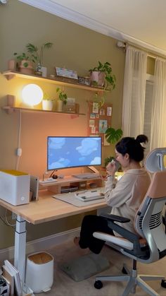 a woman sitting at a desk in front of a computer on top of a wooden desk