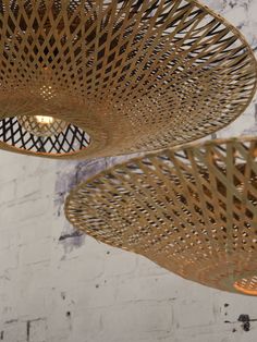 three hanging lights made out of wicker on the ceiling in a room with white brick walls