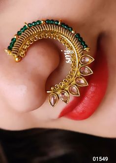 a close up of a woman's nose wearing an ear cuff with green beads