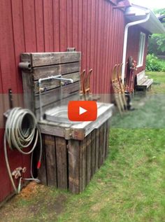 a red barn with an old water well and hoses attached to the side of it