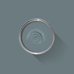 a gray paint can with a long shadow on the wall next to it's lid