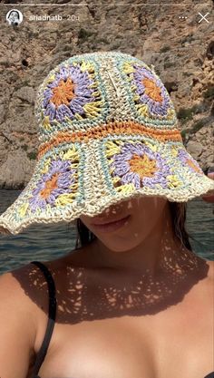 a woman wearing a crocheted sun hat by the water