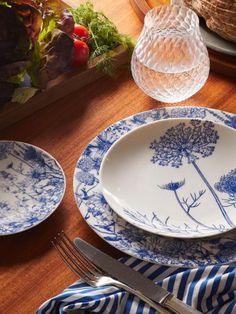 plates and utensils are sitting on a table with blue and white striped napkins