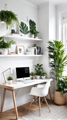 a white desk topped with a computer next to a green plant