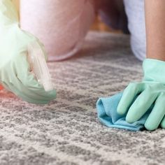 two hands with gloves cleaning carpet on the floor