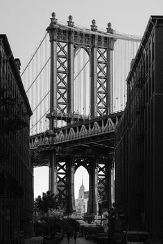 black and white photograph of the brooklyn bridge in new york city, ny with cars parked below it