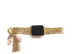 an apple watch with a gold chain and tassels on the strap, against a white background