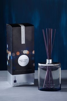 an open box next to a purple reed diffuser in front of a blue background